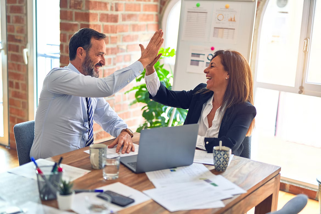 a picture of co-workers giving each other a high five in reference to digital twin helping introduce a more collaborative approach in teams